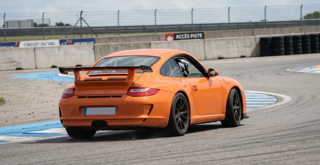 Une McLaren orange vue de trois-quarts arrière négocie un virage rapide sur circuit sous un ciel dégagé