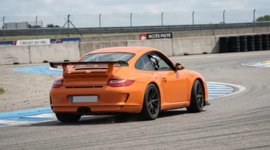 Une McLaren orange vue de trois-quarts arrière négocie un virage rapide sur circuit sous un ciel dégagé